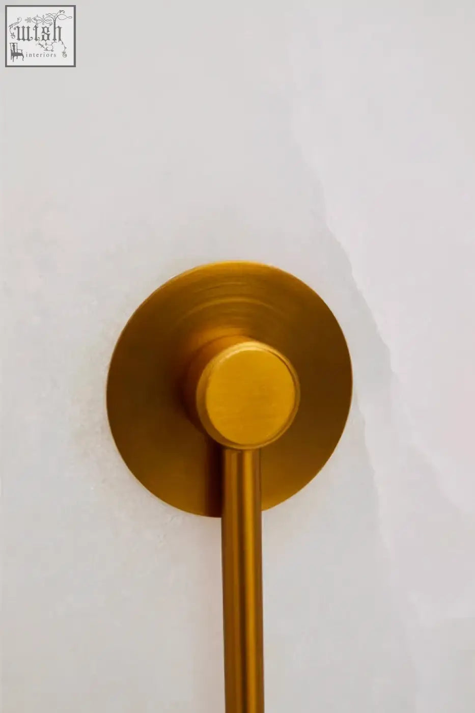 Gold-toned towel rack with a sleek modern design and polished finish mounted on a white marble wall with gold accent