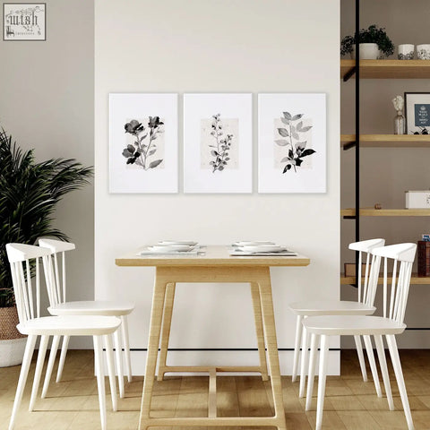Three framed grey french country botanical floral wall art canvas prints hanging above a wooden dining room table