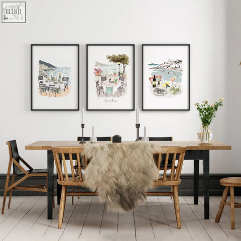 Three framed watercolor prints of mediterranean coastal dining scenes as wall art for a dining room table area