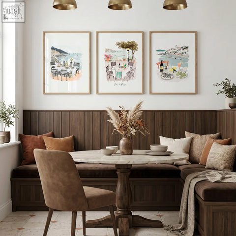 Marble-top round dining table with dark wood pedestal base next to mediterranean coastal wall art set of 3 prints in dining room