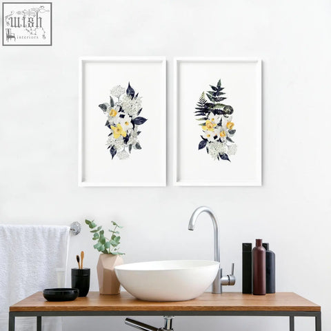 Two framed botanical wall art prints with white yellow and dark green floral design perfect for bathroom walls