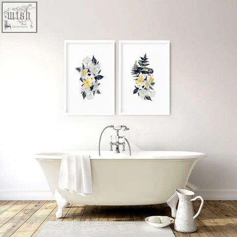 White clawfoot bathtub with silver faucet and towel beside set of 2 floral wall art prints for bathroom walls