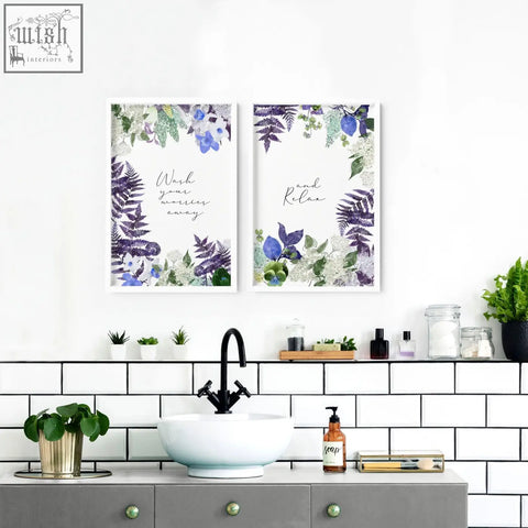 Two framed floral wall art prints with purple and blue designs featuring relaxing phrases above a bathroom sink