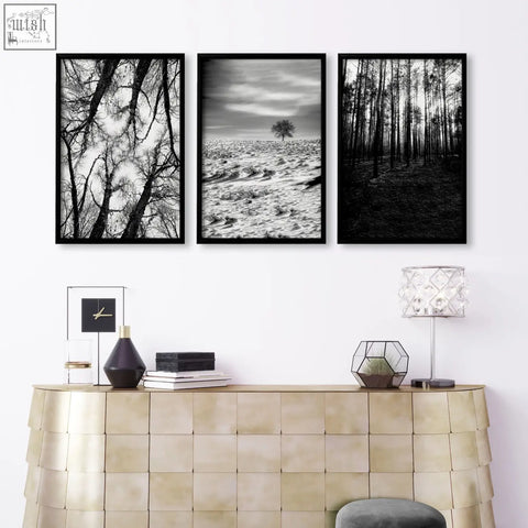 Three black-framed black and white forest and winter landscape wall art above a gold console for grey walls living room