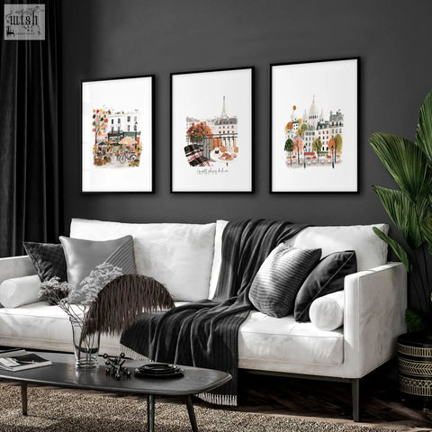 Three black framed parisian-themed watercolor wall art prints hang above a white sofa in a living room wall art living setup