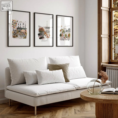 White upholstered sofa with metallic legs and cushions in living room with large paris travel wall art prints set