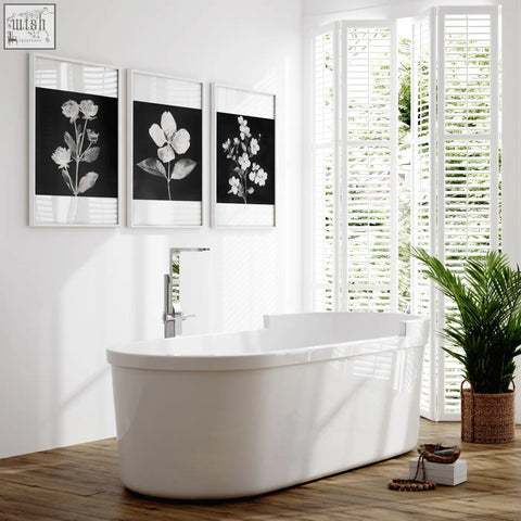 White freestanding bathtub with sleek modern design and glossy finish featured with wall art nature charcoal botanical prints set of 3