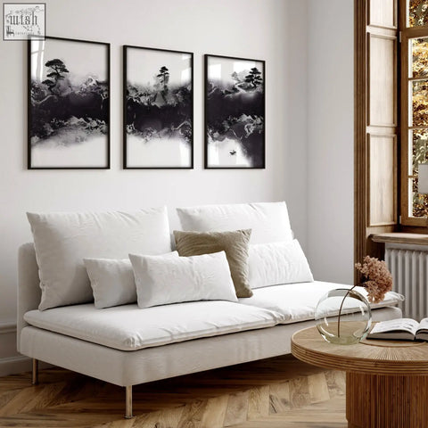 White upholstered sofa with metallic legs and cushions in a high ceiling living room with japandi art prints set of 3