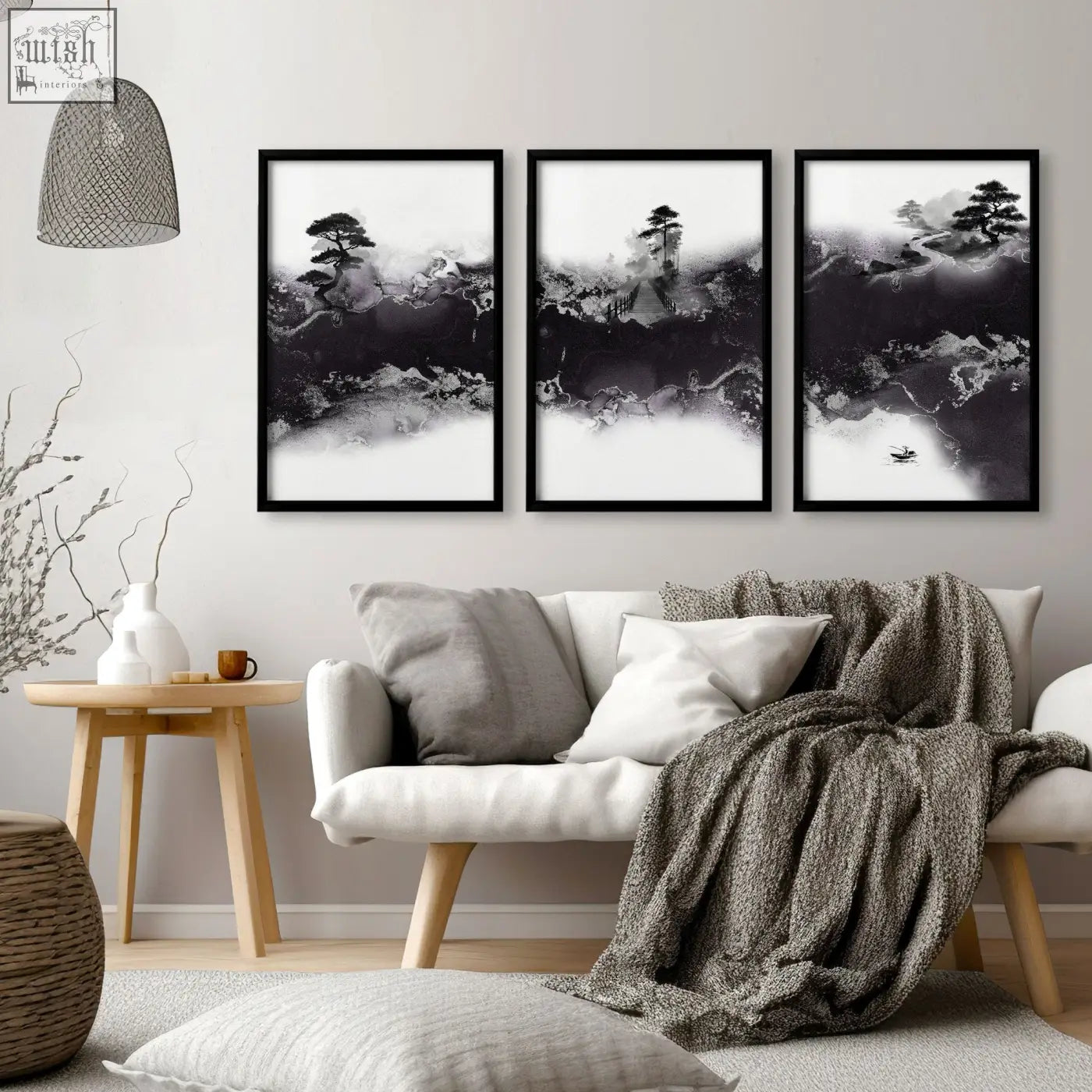 Three framed black and white mauve ink wash landscape prints hanging above a white sofa in a high ceiling living room