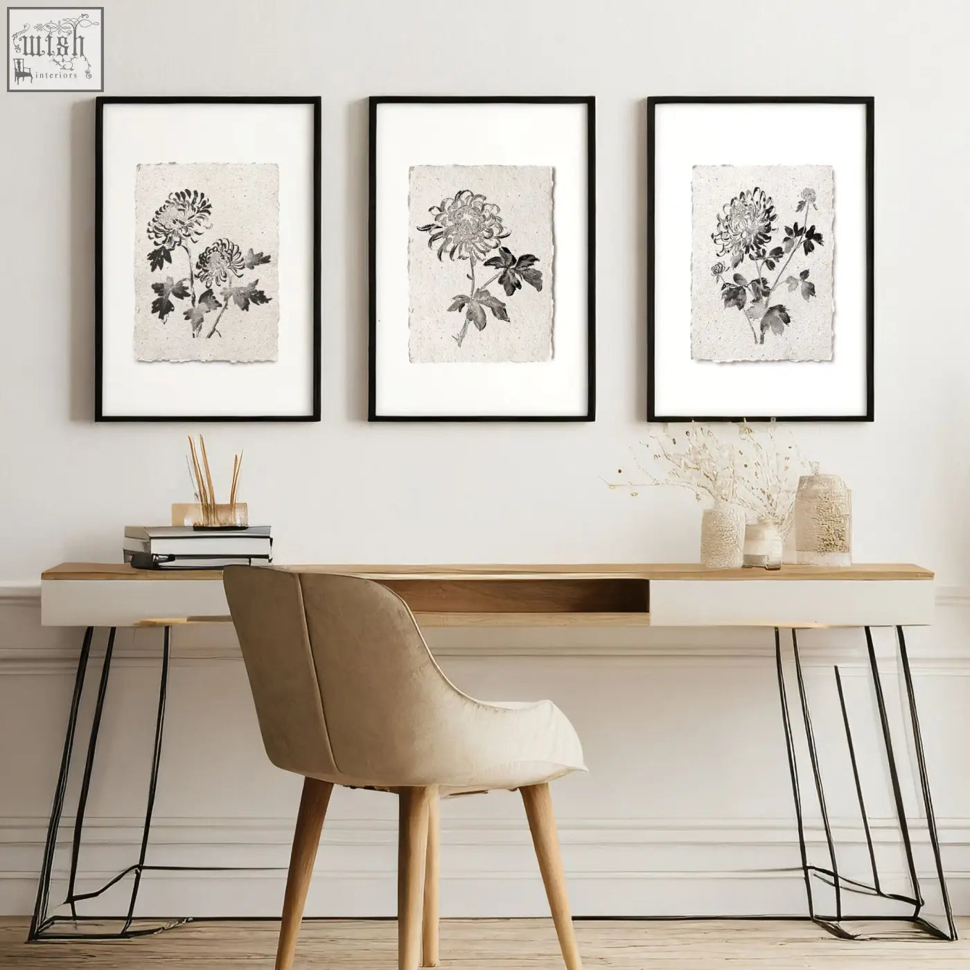 Three black-framed grey wall decor prints with monochrome chrysanthemum illustrations on textured paper above desk