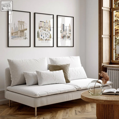 White upholstered sofa with metallic legs and cushions in living room featuring beige pastel winter in new york wall decor