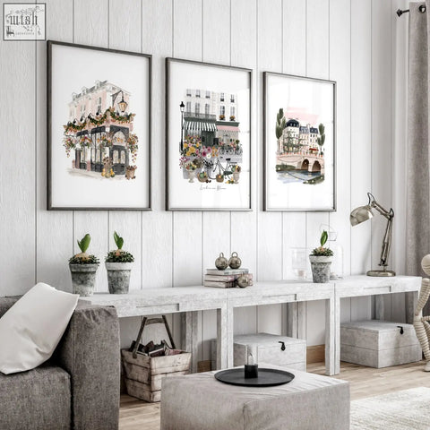 Three framed british travel wall art prints of parisian street scenes hang on a white wooden wall for living room decoration living