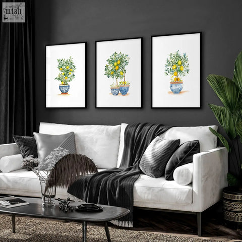 Three framed lemon tree art prints in blue and white ceramic pots hung above a modern living room sofa