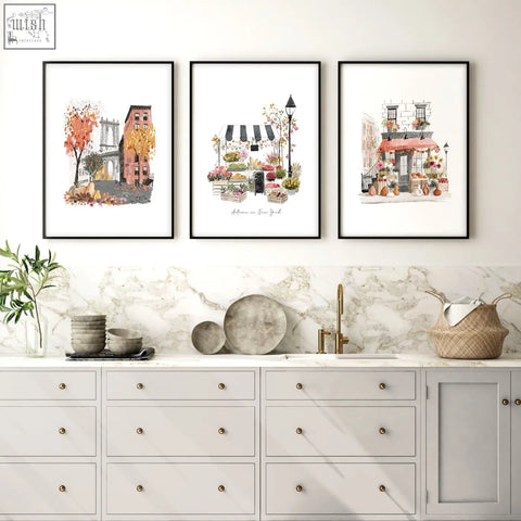 Three framed art prints of autumn in new york city travel scenes as wall hangings above a marble kitchen countertop
