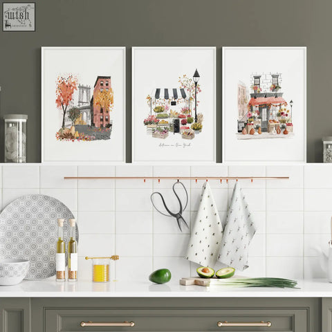 Three framed watercolor travel art prints of new york city scenes as wall hangings above a kitchen counter
