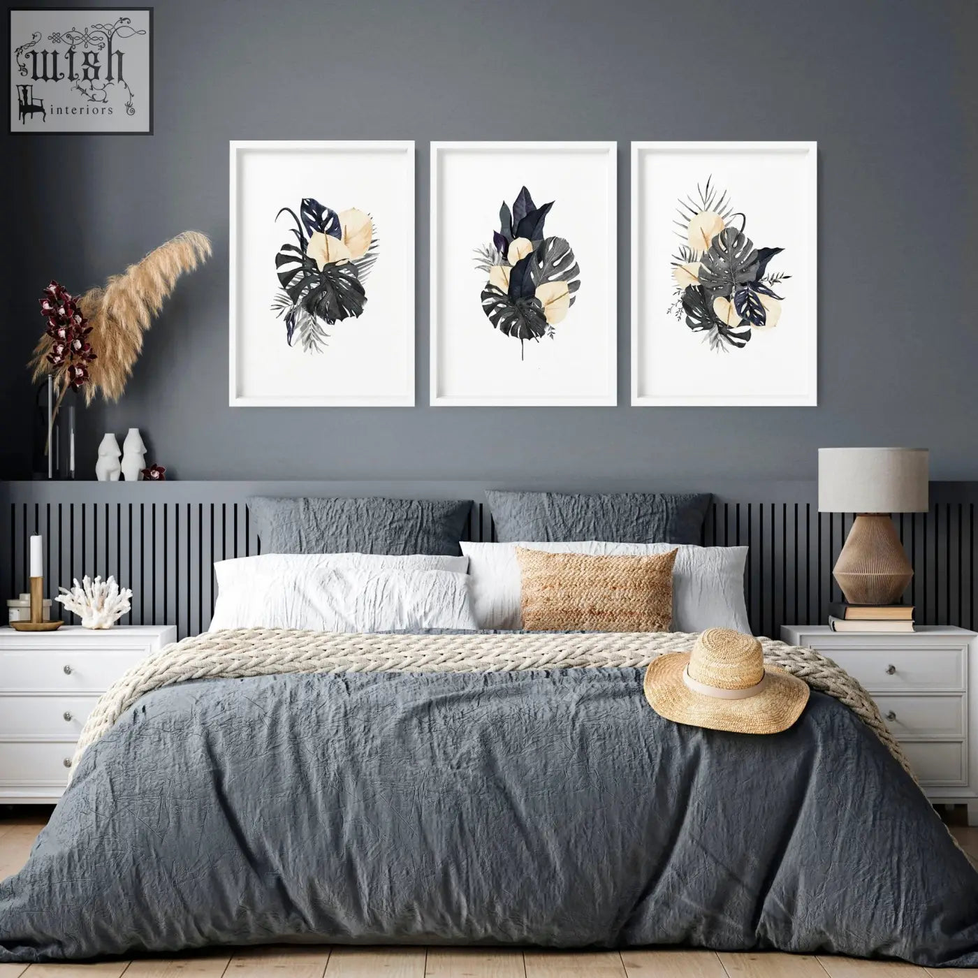 A woven straw hat with a beige band on a gray bedspread next to wall pictures featuring pink flowers wall art prints