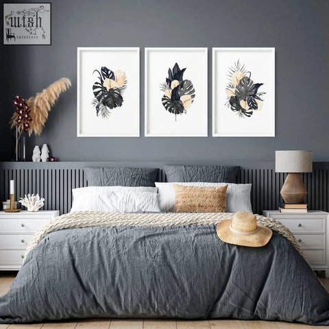 A woven straw hat with a beige band on a gray bedspread next to wall pictures featuring pink flowers wall art prints