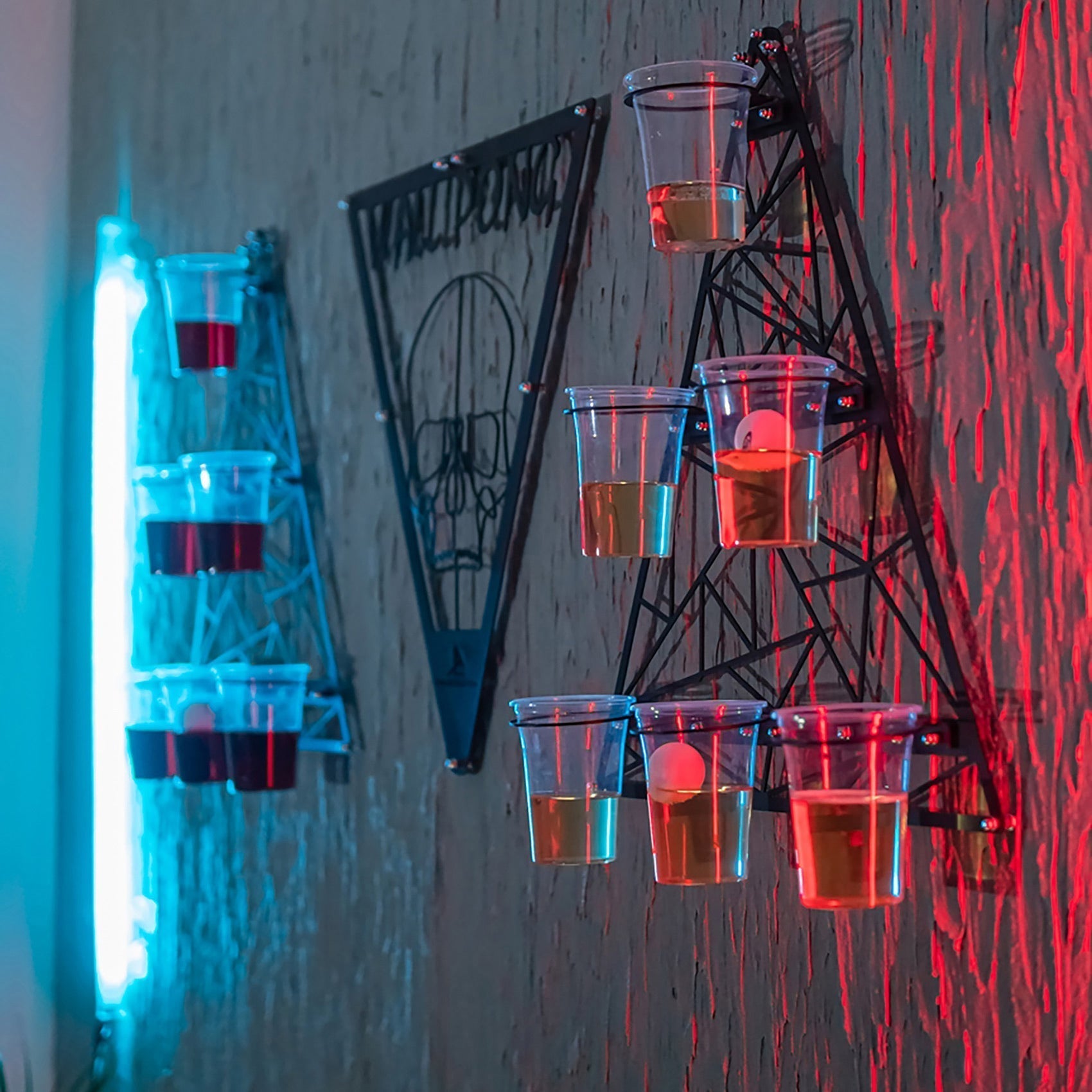 Black metal wall pong shot glass holder with clear plastic cups arranged in opposing teams cups triangle formation