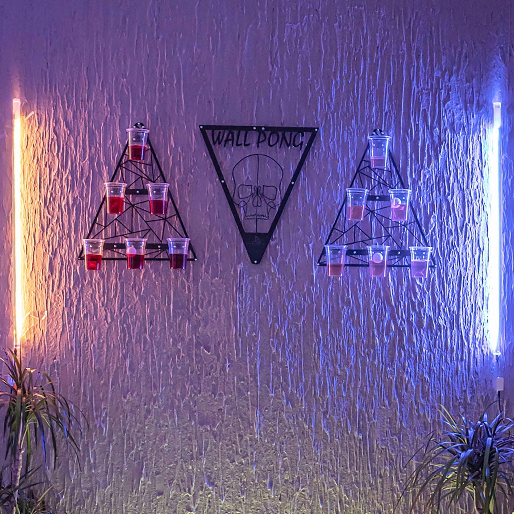Black metal wall pong drinking game with skull design and triangular racks for opposing teams cups setup