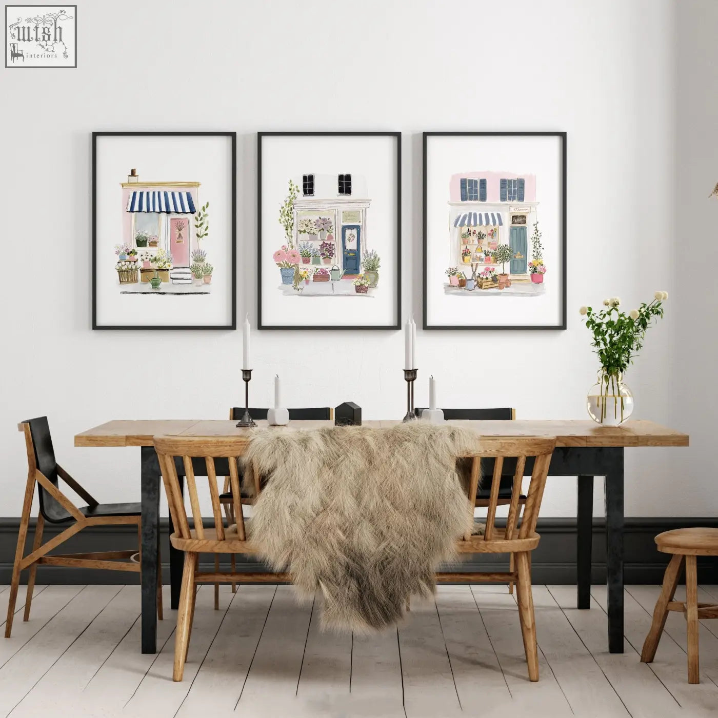 Three framed blue flower shop wall prints hang above a wooden dining room table for a cozy country cottage look