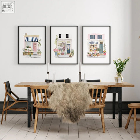 Three framed blue flower shop wall prints hang above a wooden dining room table for a cozy country cottage look
