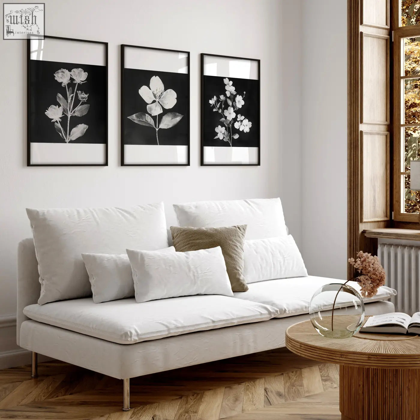 White upholstered sofa with metallic legs and cushions beside a set of 3 black and white botanical wall prints for living room french country style