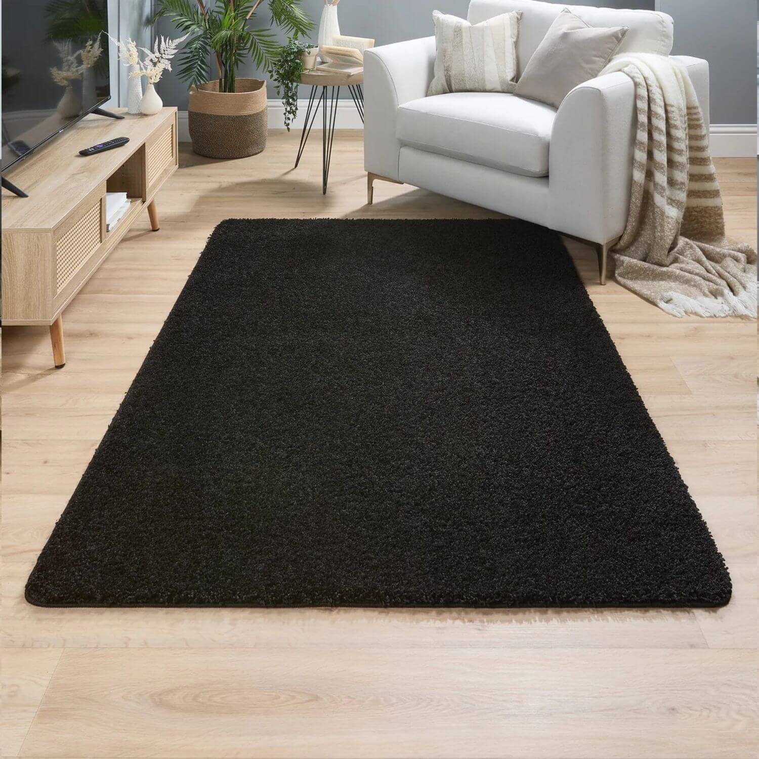 Black plush rectangular washable black shaggy rug with soft shaggy texture and slightly frayed edges