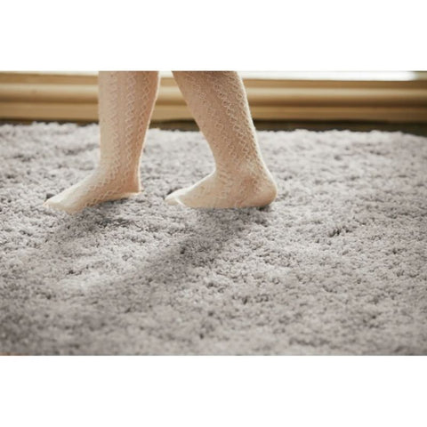 Child wearing beige lace-patterned tights on a washable ghost grey shaggy rug perfect for cozy rooms