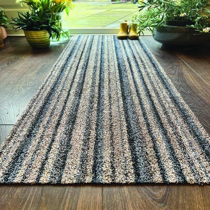 A washable ribbon mat with dark and light gray striped texture on wooden floor perfect for easy cleaning