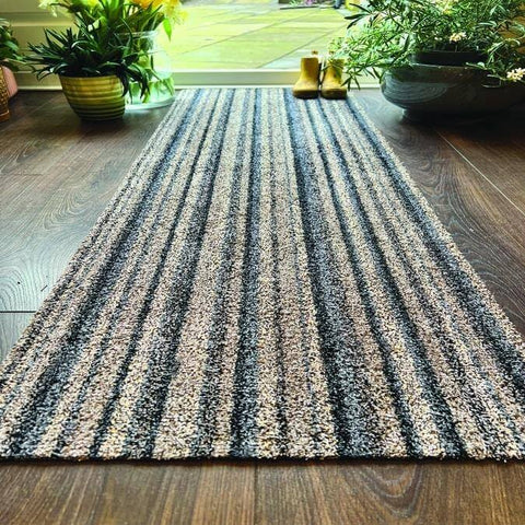 A washable ribbon mat with dark and light gray striped texture on wooden floor perfect for easy cleaning