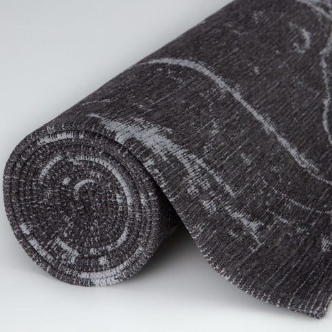 A rolled-up washable rug carina dark grey with a subtle abstract pattern and textured weave in dark grey tones