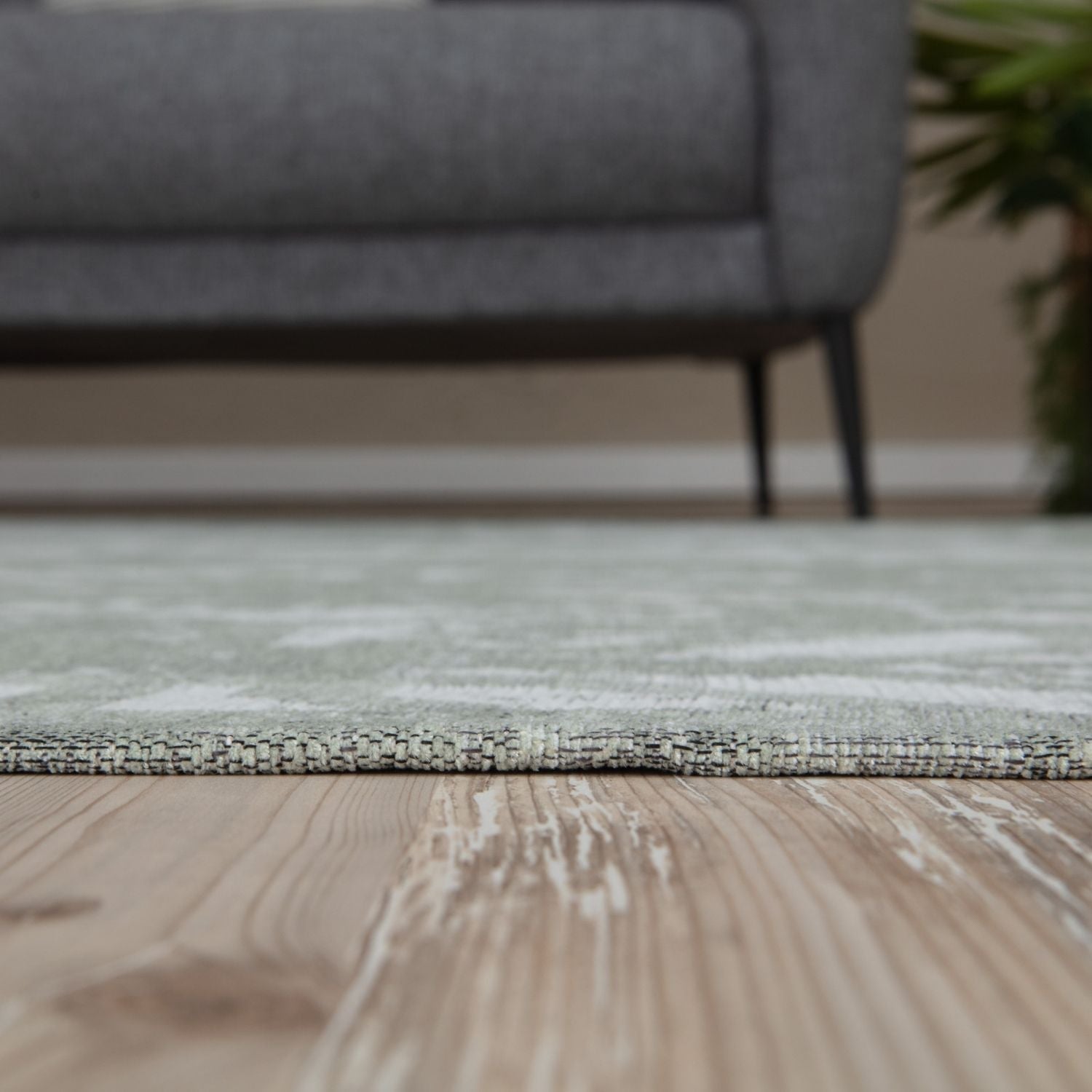 A soft washable rug carina green with light green and white abstract pattern on textured weave wooden floor