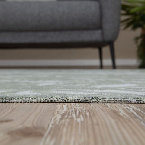 A soft washable rug carina green with light green and white abstract pattern on textured weave wooden floor