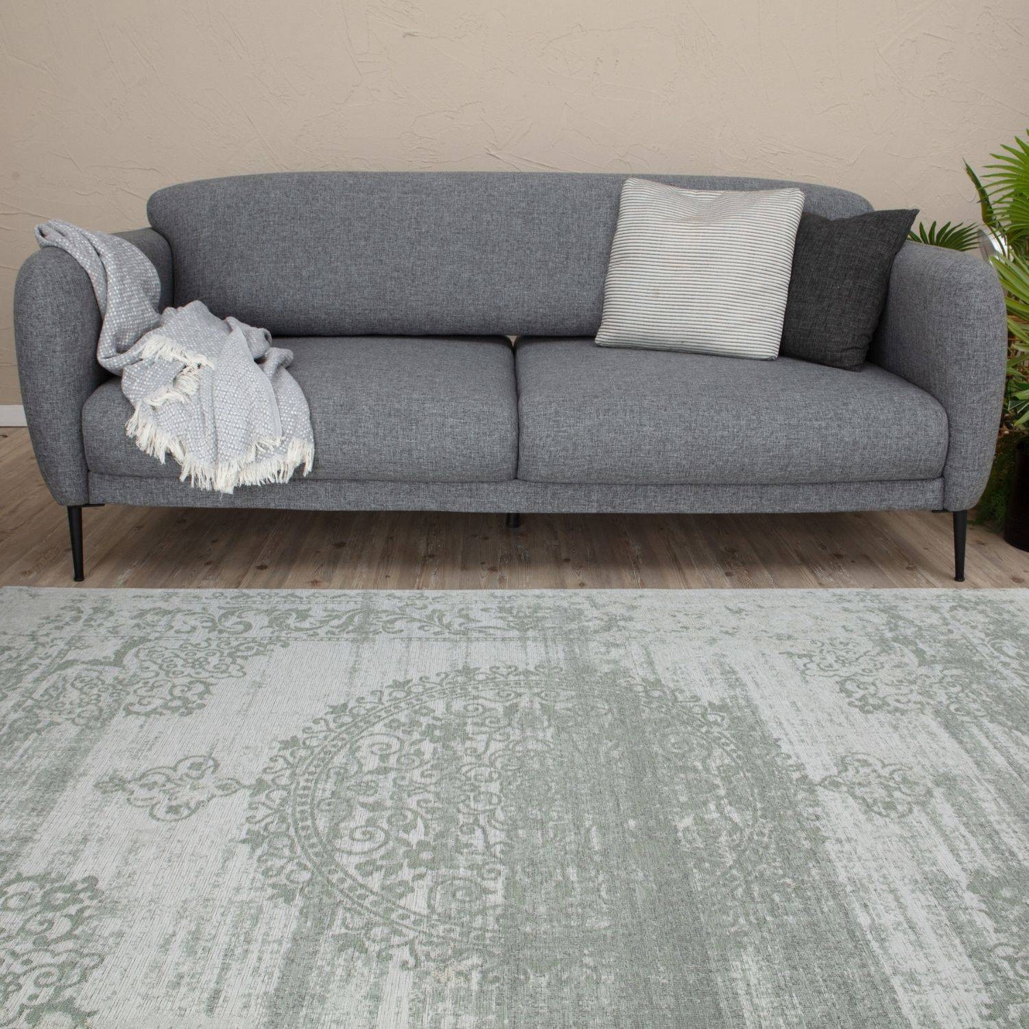 Gray textured fabric sofa with black metal legs and pillows next to washable carina green rug 6944