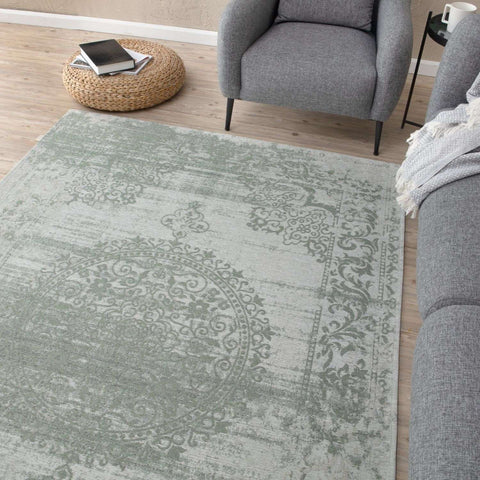 A light gray washable rug carina green with a vintage distressed floral green rug pattern and ornate circular design