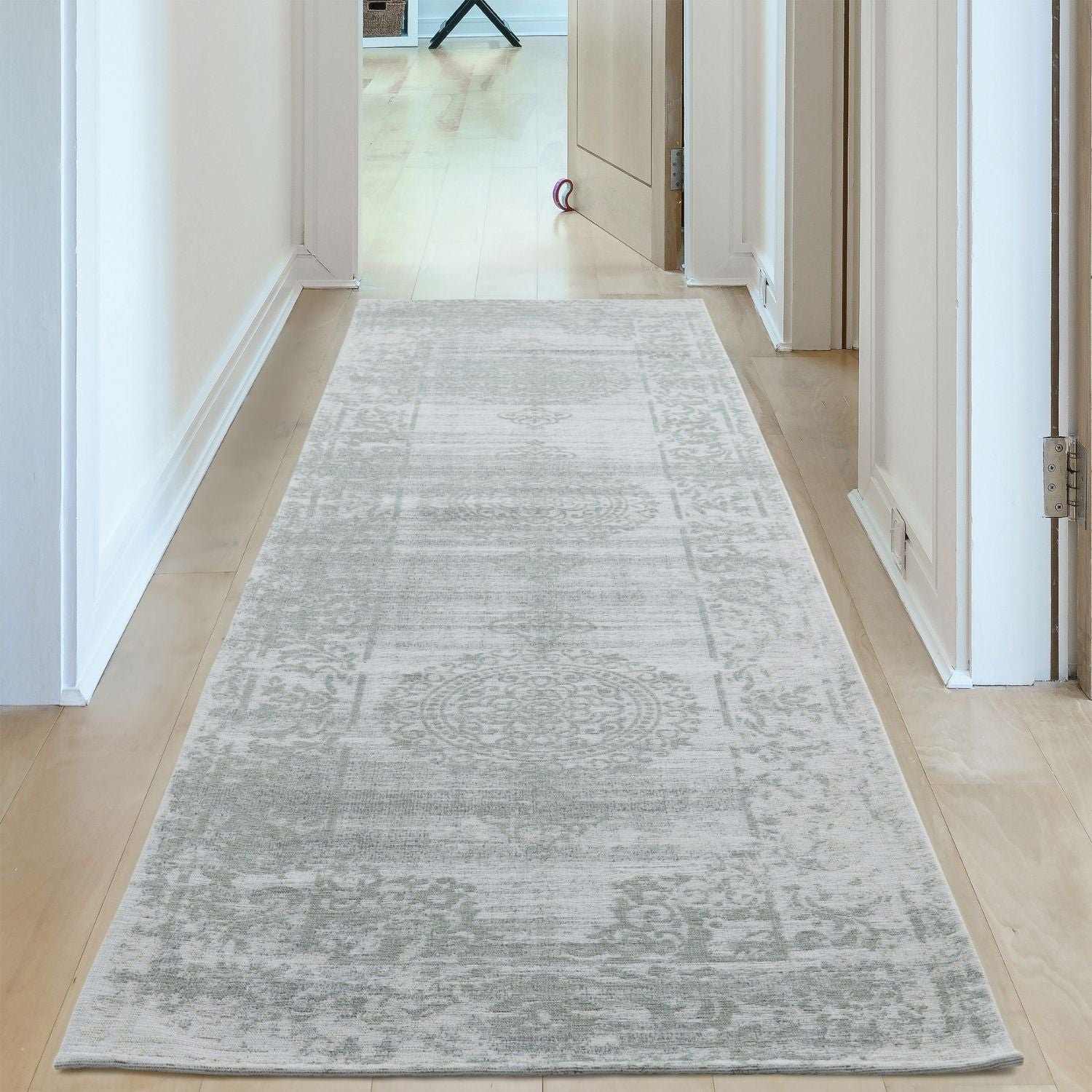 A long light gray washable runner rug with a vintage pattern and distressed texture featuring carina green tones