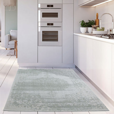 A soft washable rug carina green with a vintage floral pattern in light greenish blue and subtle distressing