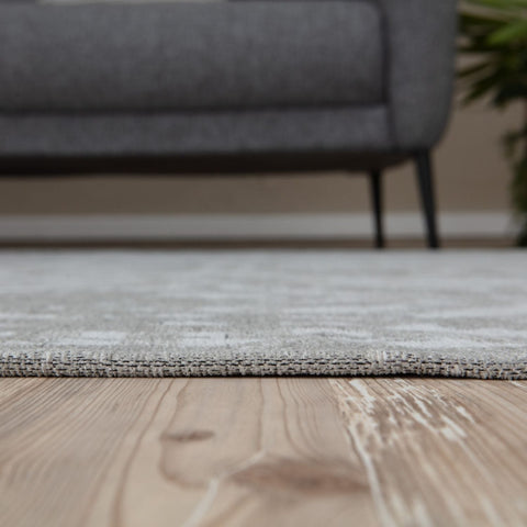 Gray washable rug carina grey with subtle geometric pattern and textured edge on light wood flooring