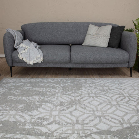 Gray textured fabric sofa with black metal legs and two throw pillows complements washable rug carina grey 6932