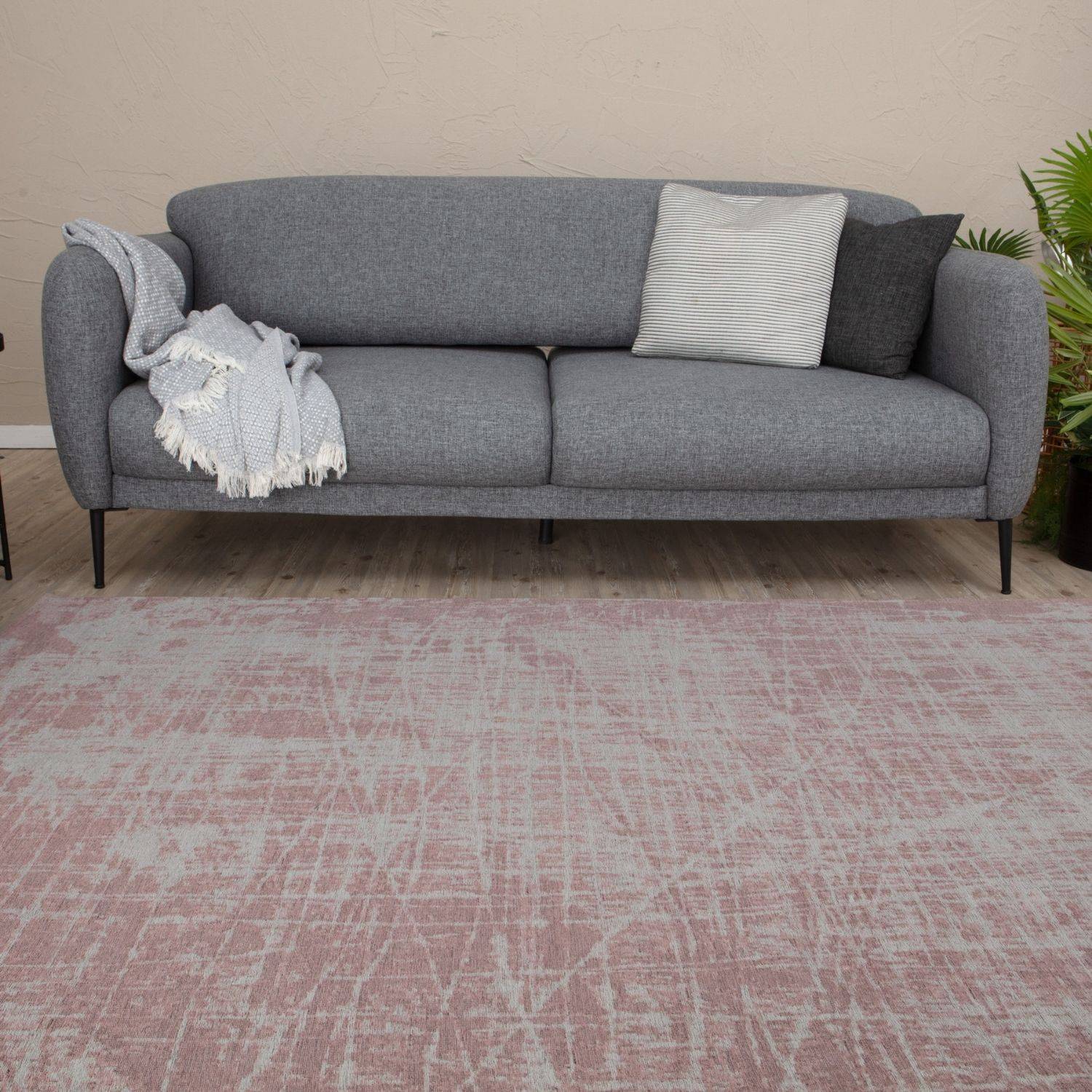 Gray textured fabric sofa with black legs and decorative pillows next to washable rug carina pink 6920p
