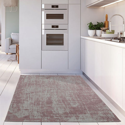 A rectangular distressed mauve and gray washable rug carina pink with vintage texture on a white wooden floor