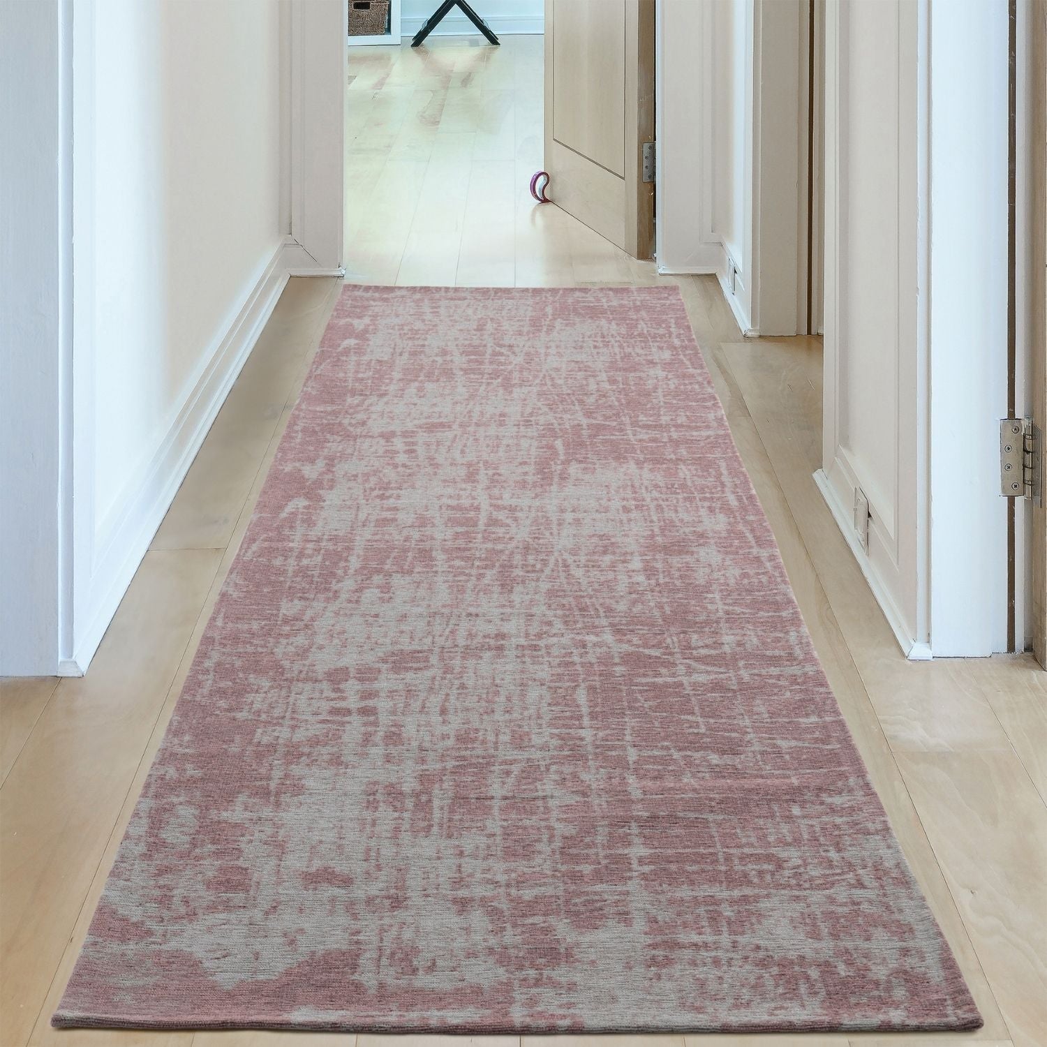 A soft pink and gray distressed washable rug carina with a vintage-inspired textured pattern perfect for runners
