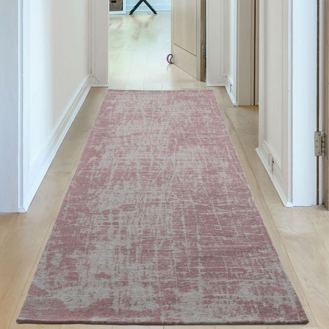 A soft pink and gray distressed washable rug carina with a vintage-inspired textured pattern perfect for runners