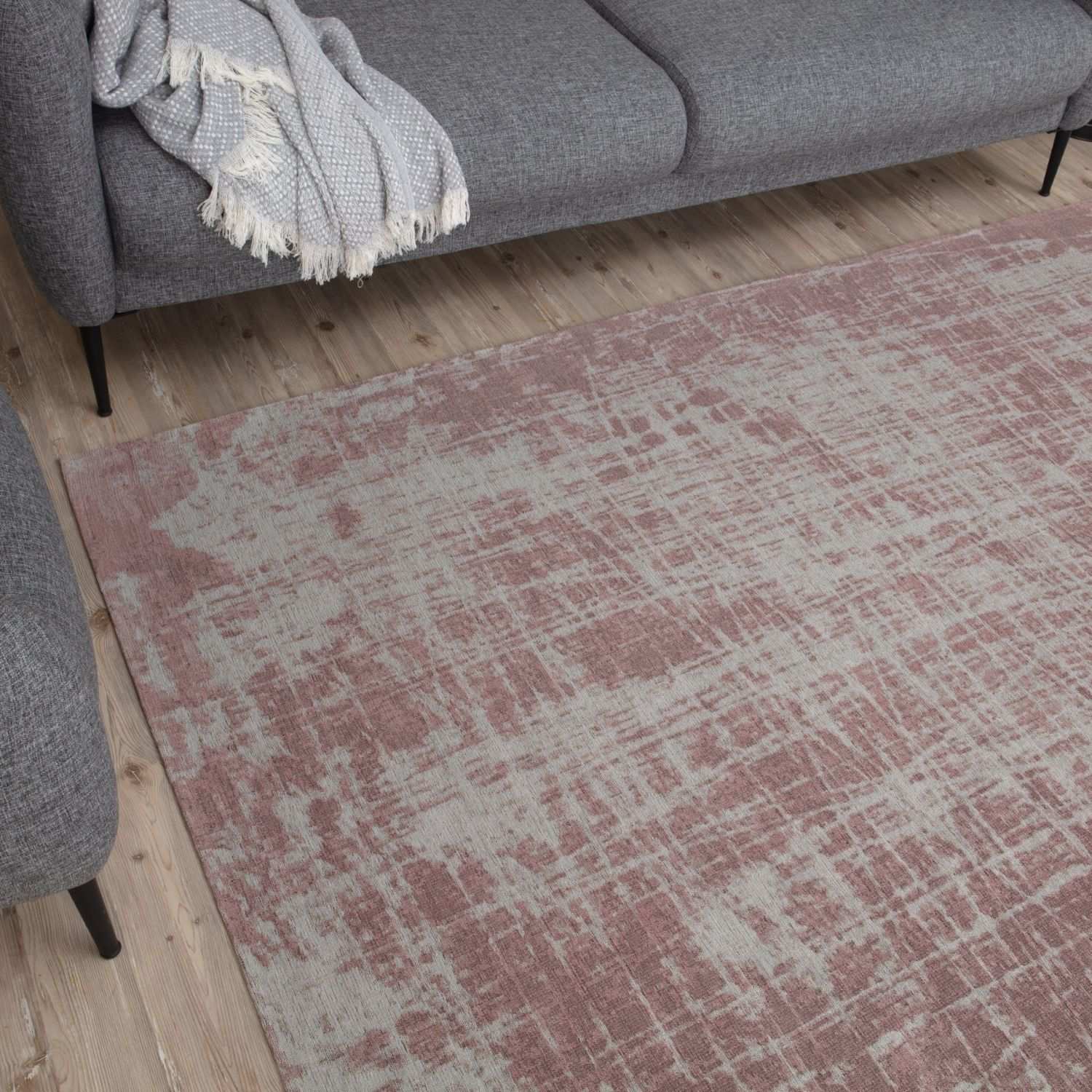 A soft washable rug carina in pink with a faded abstract pattern on a wooden floor
