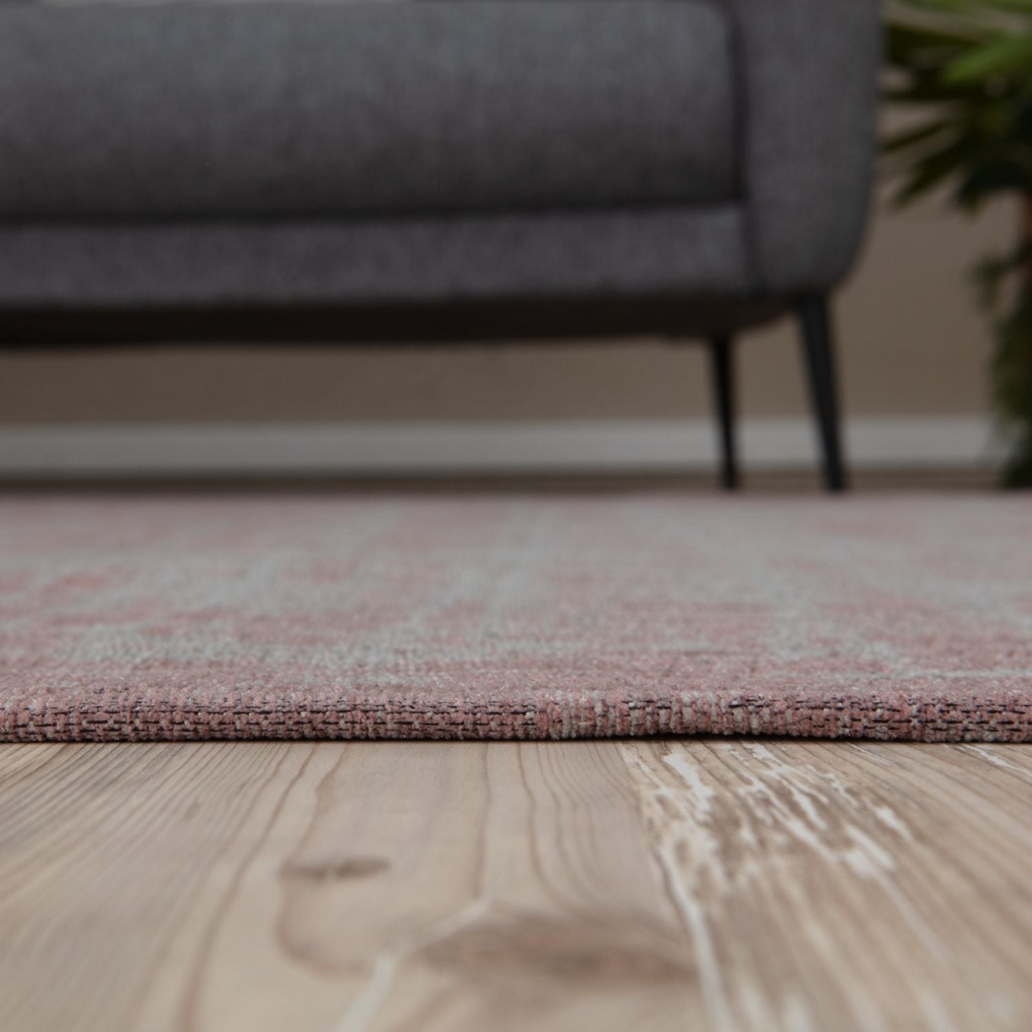 A soft pink washable rug carina with a subtle woven pattern on light wood flooring perfect for any room