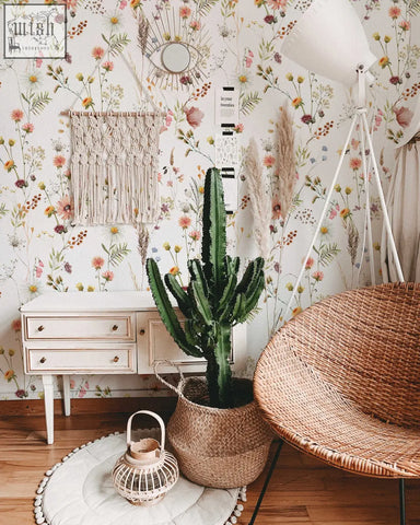 A tall green cactus in a woven wicker basket complements soft botanical field floral peel and stick wallpaper for living space