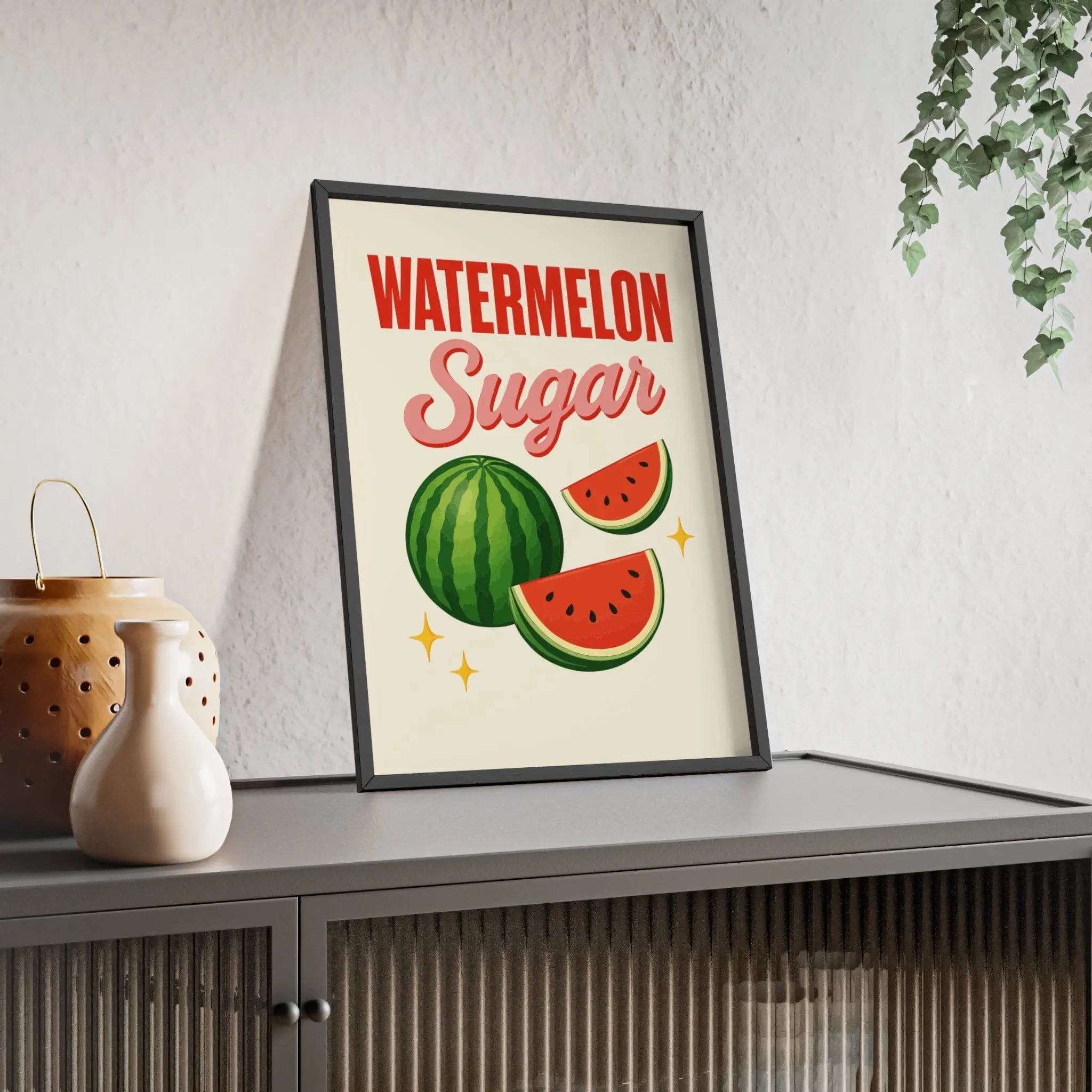 A framed harry styles poster with bold red and pink watermelon sugar text and green watermelon illustrations on off-white background