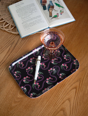 Black rectangular waves of love tray with delicate pink and green floral pattern and wavy outlines around blossoms