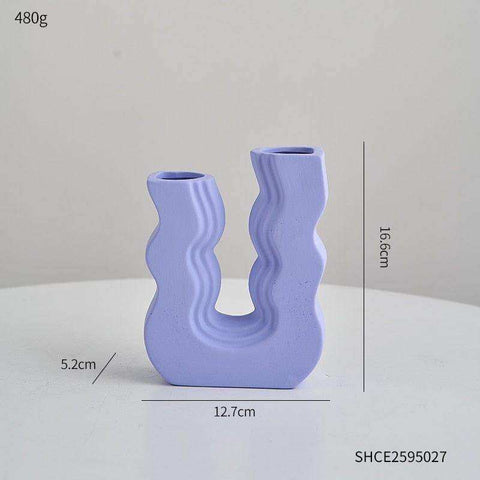 A light purple ceramic wavy wonder vase with a u-shaped design and two curved openings for decoration