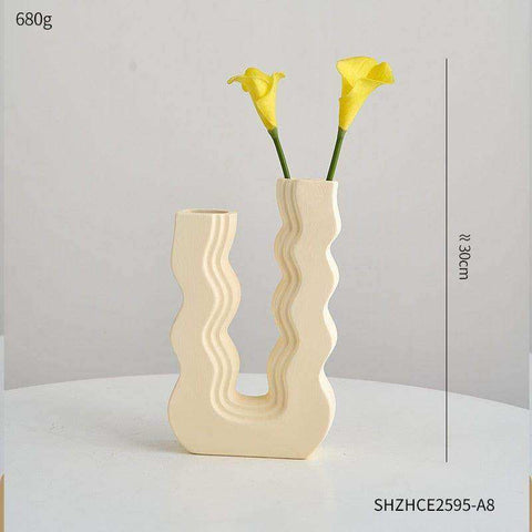 Cream-colored ceramic wavy wonder vase with a modern design and two openings holding yellow calla lilies